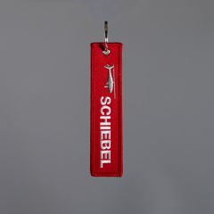Front of red key ring with white embroidered “SCHIEBEL” logo and drone